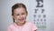 Adorable child girl laughing after vision test on eye chart, healthy sight