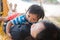 Adorable child hugs mother lying on beach hammock and acts like a baby