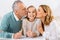 adorable child looking at camera while grandparents kissing her