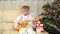 Adorable child playing at guitar close Christmas tree, traditional suit