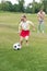 adorable child in sunglasses playing with soccer ball while father standing behind