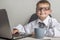 An adorable child is working on a laptop in suit and glasses. Little boss in the office. Children pretend to be adults