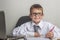 An adorable child is working on a laptop in suit and glasses. Little boss in the office. Children pretend to be adults