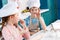 adorable children in chef hats and aprons smiling each other while cooking together