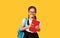 Adorable Chinese Schoolgirl With Backpack Holding Book On Yellow Background