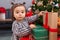 Adorable chinese toddler decorating christmas tree at home