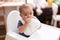 Adorable chinese toddler drinking water sitting on dinner chair baby at home