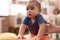 Adorable chinese toddler leaning on stool standing at kindergarten