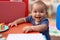 Adorable chinese toddler leaning on table standing at kindergarten