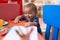 Adorable chinese toddler leaning on table standing at kindergarten