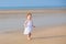 Adorable curly baby girl walking on beach