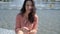 Adorable, cute brunette woman, sitting next to city fountain in the summer