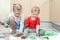 Adorable cute caucasian little blond siblings children enjoy having fun painting with brush and palm at home indoors