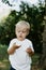 Adorable Cute Little Blond Hair, Blue Eyed Kid Boy in White Tee Shirt Playing and Discovering New Things Outside in Nature