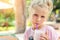 Adorable cute preschooler caucasian blond girl portrait sipping fresh tasty strawberry milkshake coctail at cafe outdoors.