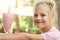 Adorable cute preschooler caucasian blond girl portrait sipping fresh tasty strawberry milkshake coctail at cafe outdoors.