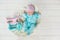 Adorable cute sweet baby girl sleeping in white basket on wooden floor with two toy tilda rabbits