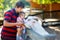 Adorable cute toddler girl and young father feeding little goats and sheeps on a kids farm. Beautiful baby child petting