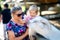 Adorable cute toddler girl and young mother feeding little goats and sheeps on a kids farm. Beautiful baby child petting