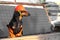 Adorable dachshund in equipment of handyman and in protective orange helmet is at construction site.