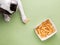 Adorable dog stares with anticipation at a tray of dog treats lying atop a vibrant green background