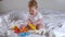 Adorable eight-month-old girl playing with pyramid toy sitting on the bed