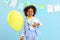 Adorable ethnic kid with birthday present and balloon in hands