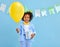 Adorable ethnic kid with birthday present and balloon in hands