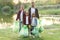 Adorable family of parents and kids hold plastic rubbish bags after cleanup surrounding territory near lake