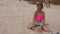 Adorable female child playing with sand and sitting on beach