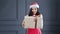 Adorable female Santa Claus gives big gift box in Christmas time at studio medium shot