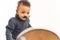 Adorable funny biracial baby boy with black fake mustache looking at himself in the mirror over white background. Studio