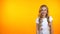 Adorable girl laughing happily standing on orange background, humor and jokes