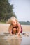 Adorable girl play with wet sand on sunset ocean beach