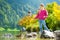 Adorable girl playing by Konigssee lake in Germany on warm summer day. Cute child having fun feeding ducks and throwing stones int