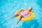 Adorable girl relax on yellow life ring in pool at protical beach resort