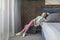 Adorable girl sitting on pouffe near the bed at home