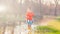 Adorable girl splashing puddle water in forest