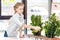 Adorable girl watering green plants in office