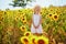 Adorable girl in white dress and straw hat in a field of sunflowers in Provence, France