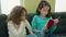 Adorable girls reading book sitting on sofa at home