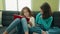 Adorable girls reading book sitting on sofa at home