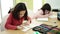 Adorable girls students sitting on table drawing on notebook at classroom