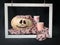 Adorable Halloween pumpkin with a pink scarf next to white and pink candles in white frame on black background