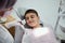 Adorable handsome elementary aged boy sitting in dentists chair during paediatric dentist visit in modern white dental clinic,