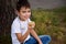 Adorable handsome schoolboy, elementary aged child sitting on the green grass of the park, eating an apple while resting during