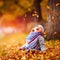 Adorable happy baby girl catching the fallen leaves, playing in