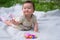 adorable and happy baby girl hat embraces the joys of playfulness on a soft blanket playing with little toy. Laughing as she