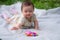 adorable and happy baby girl hat embraces the joys of playfulness on a soft blanket playing with little toy. Laughing as she