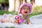 adorable and happy baby girl hat embraces the joys of playfulness on a soft blanket playing with little toy. Laughing as she